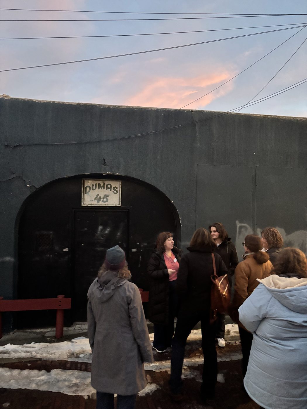 A tour group gathered at the arched stone entrance of a historic Butte building