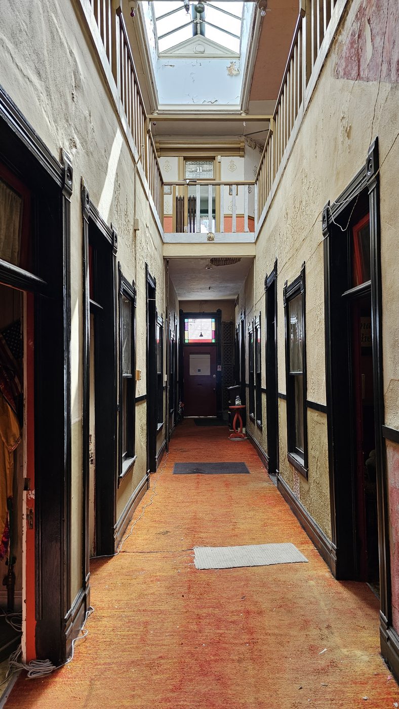 A skylit interior corridor of the Dumas, doors lining a worn runner